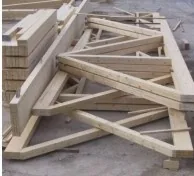 Abgebundene Holzbinder liegen gestapelt auf dem Bauplatz