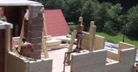 Rohbau eines Blockhauses, Wände aus Holzbohlen werden aufgesetzt