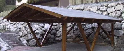 Holz-Carport mit Satteldach vor einer Steinmauer