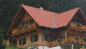 Holzhaus mit rotem Dach und umlaufenden Holzbalkonen am Hang