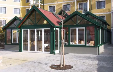 Grüner Holz-Wintergarten mit mehreren Giebeln an einem Hotel